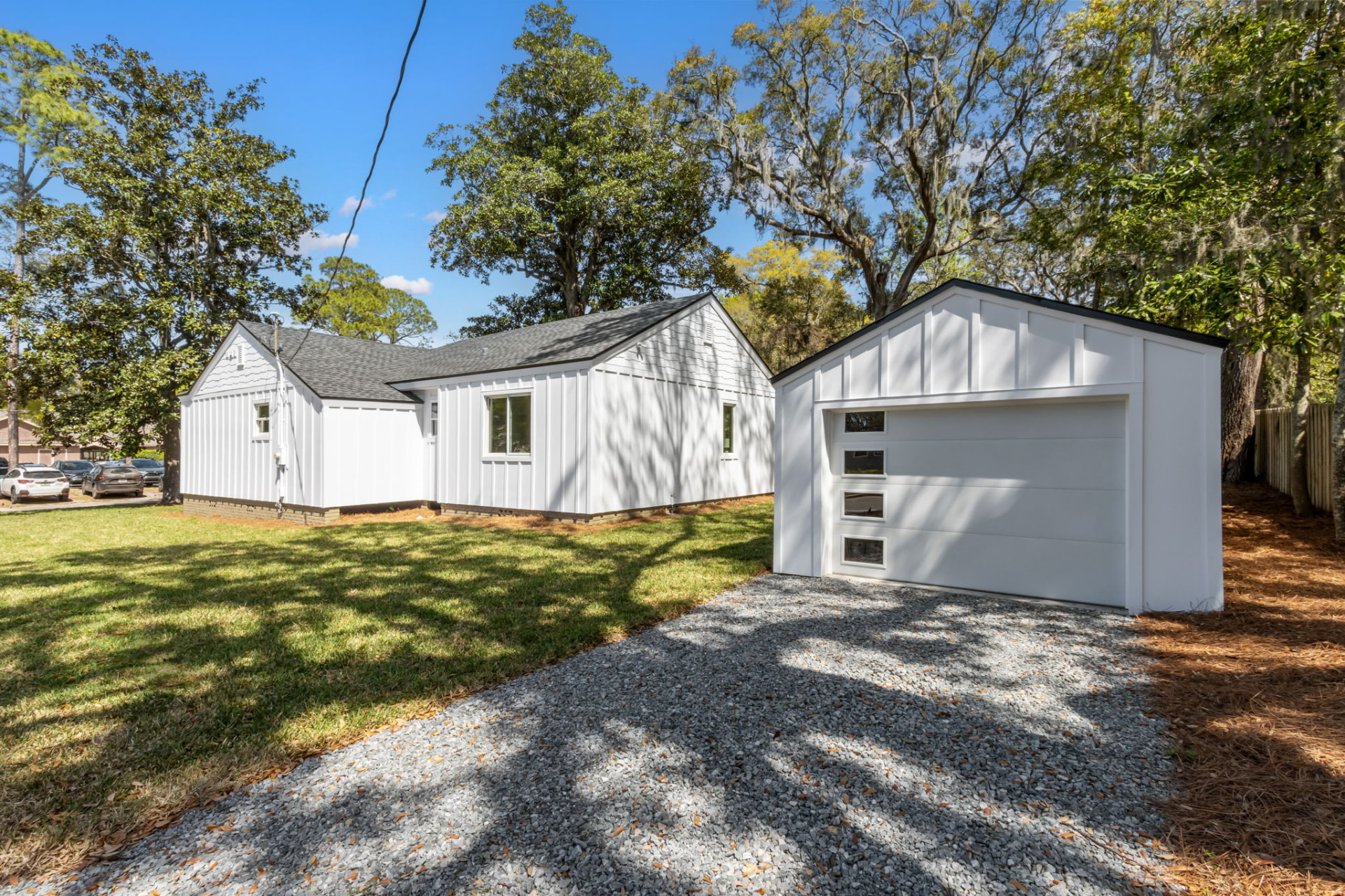 Rear exterior and detached garage with gravel drive and mature oak trees