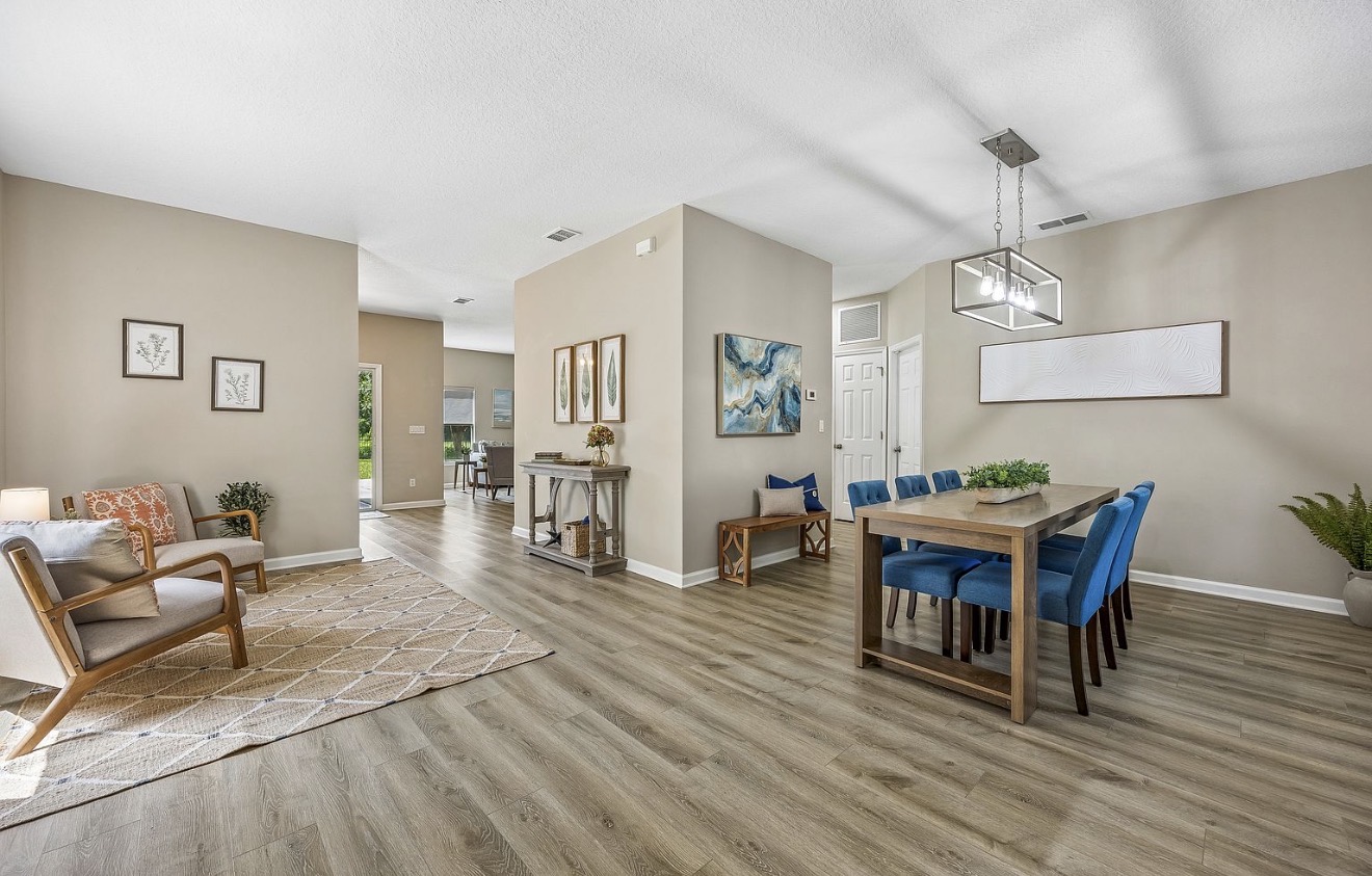 Open dining and sitting area with a wood table, blue upholstered chairs, and coastal abstract art