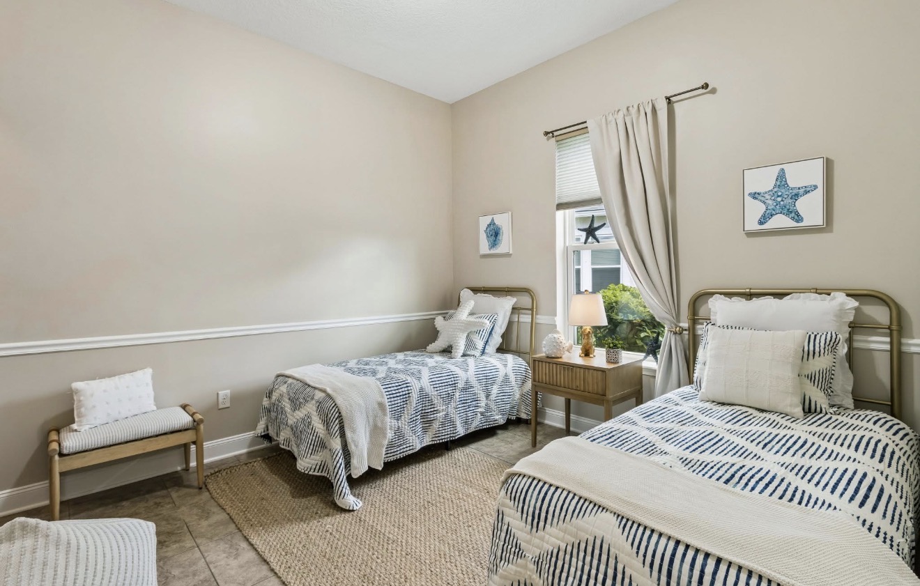 Guest bedroom with twin brass beds, navy striped bedding, and starfish wall art