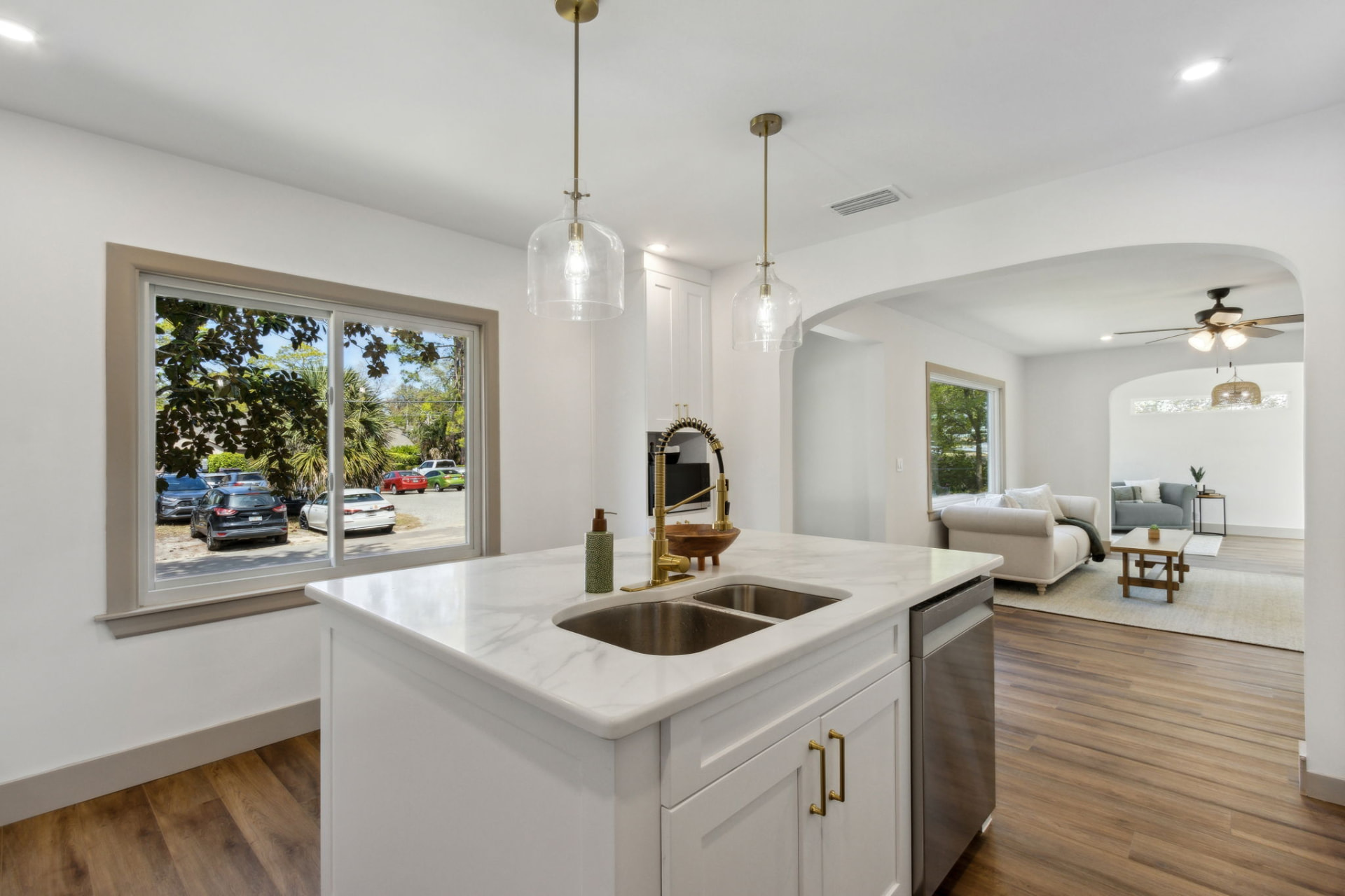 Kitchen island detail with brass faucet and view through to the staged living room