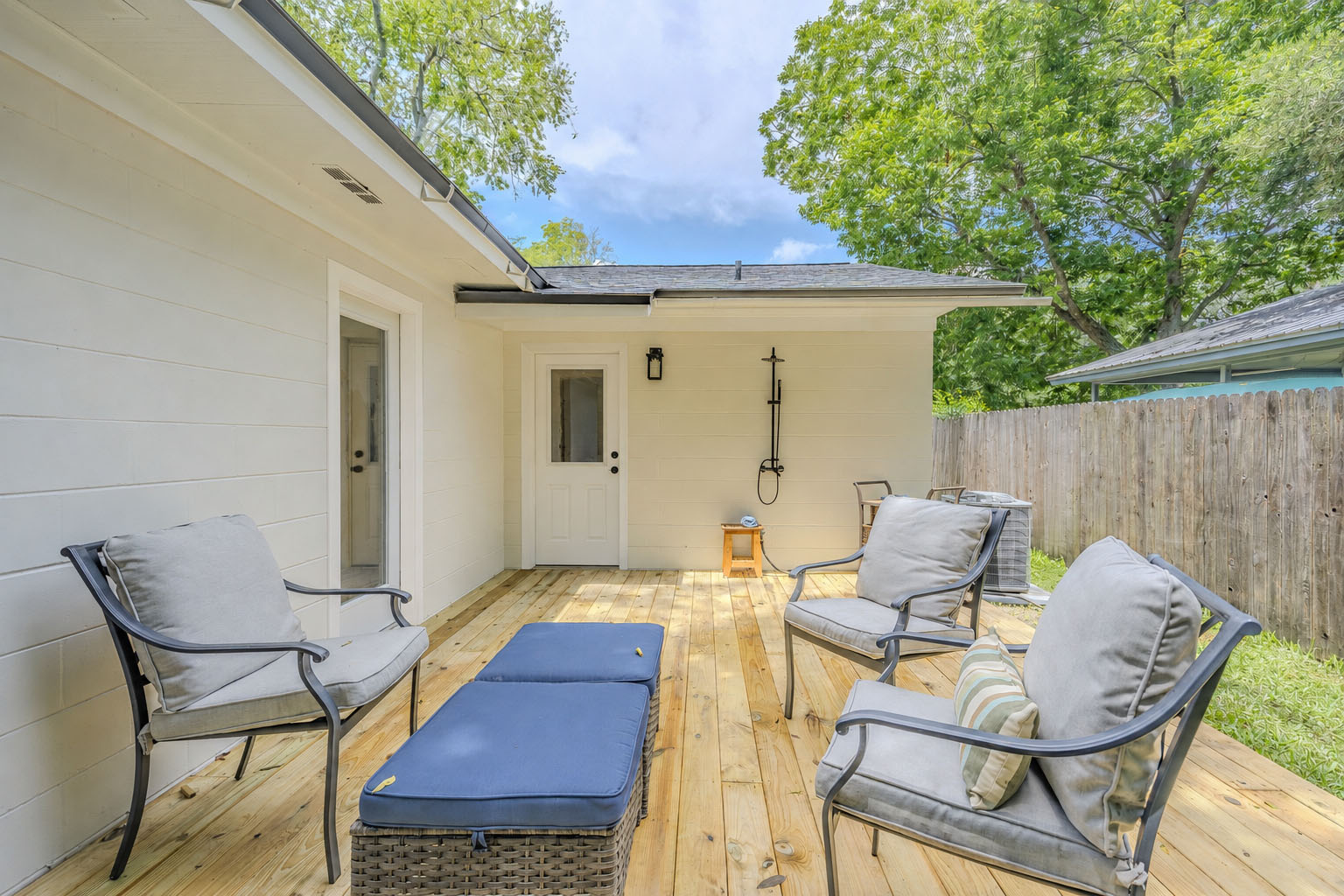 Back patio deck staged with cushioned outdoor seating and an outdoor shower