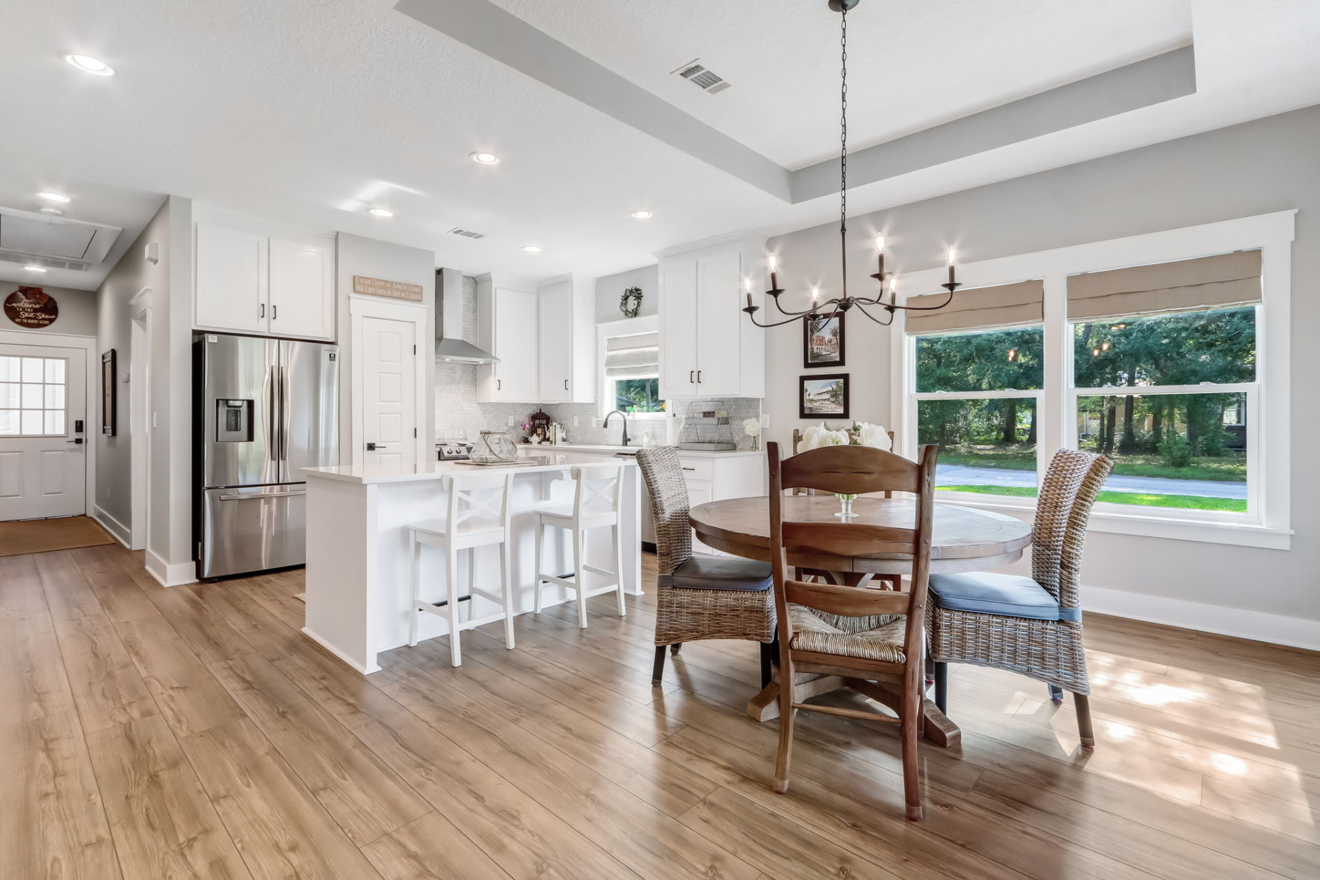 Open-concept kitchen and dining area staged with a round wood table, woven chairs, and counter stools at Beech Street