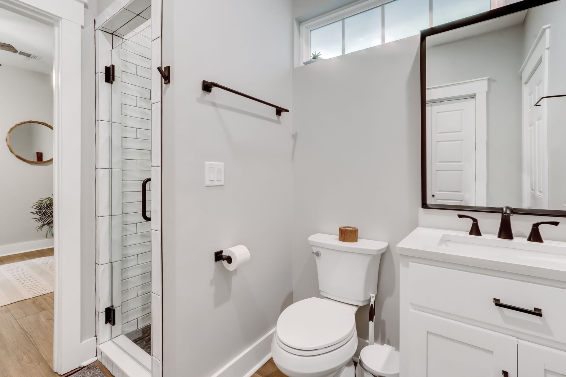 Guest bathroom with framed mirror, quartz vanity, and glass tile shower
