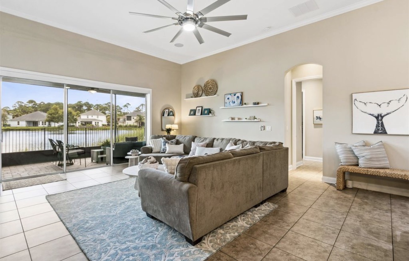 Living room open to the lanai with lake views, whale-tail art, and coastal accents