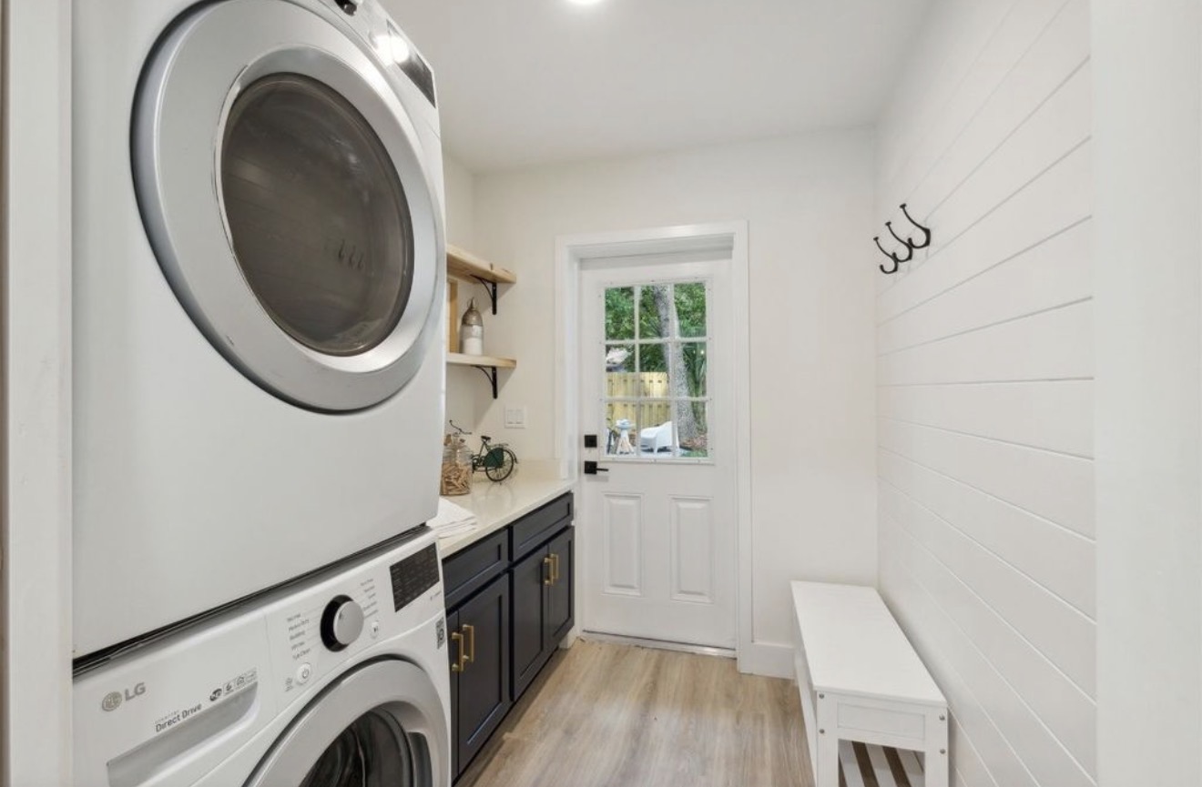 Laundry and mudroom with navy cabinetry, quartz counter, and shiplap wall