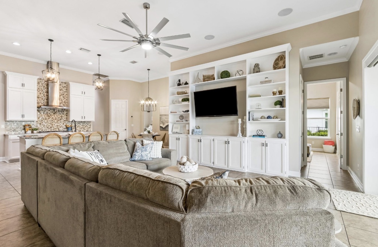 Open living and kitchen area with built-in media wall and white cabinetry at Ocean Breeze