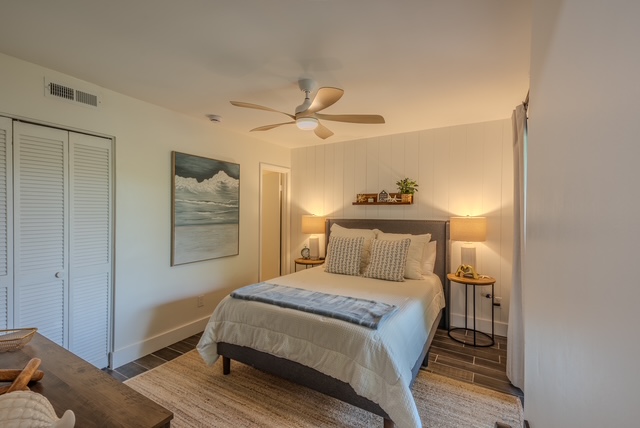 Guest bedroom with neutral linens, ocean artwork, and a jute rug