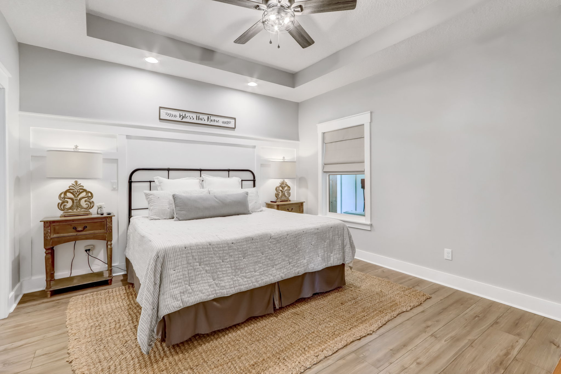 Primary bedroom staged with an iron bed, layered white linens, and board-and-batten accent wall