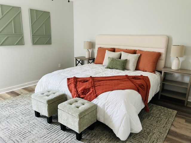 Staged bedroom featuring a cream upholstered bed with terracotta and sage green accents