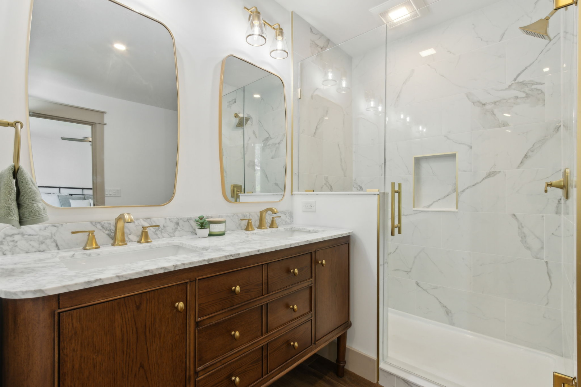 Primary bathroom with double marble vanity, brass fixtures, and glass shower