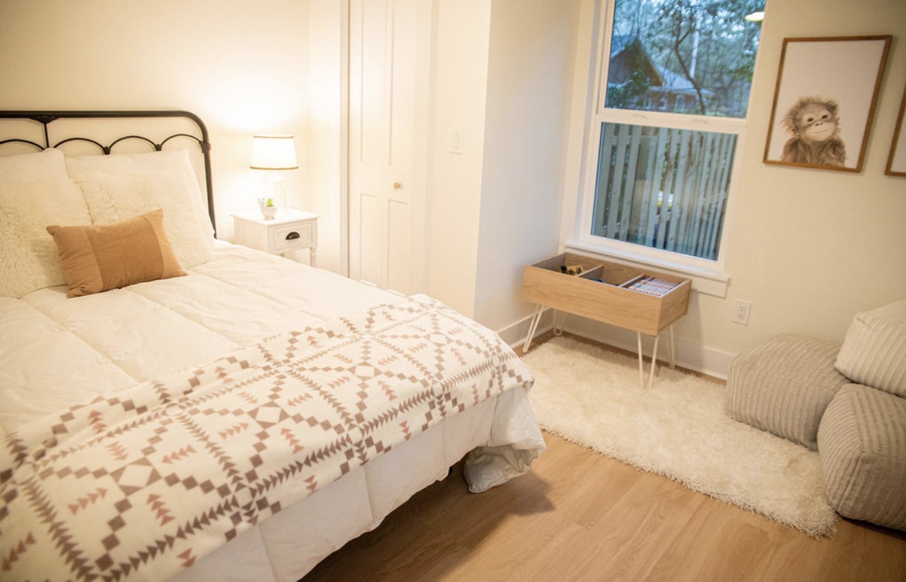 Guest bedroom staged with warm neutral bedding and soft textures