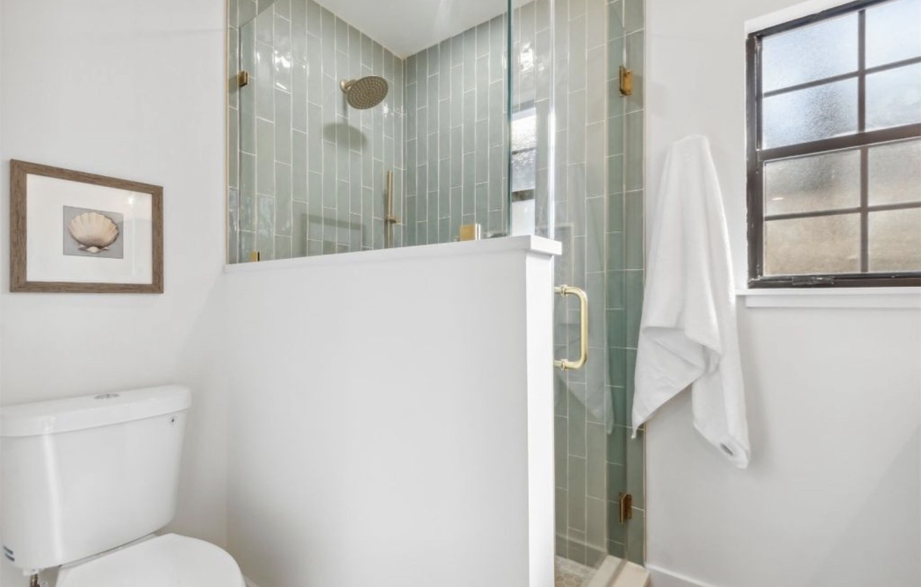 Walk-in shower with vertical sea glass tile and brass hardware