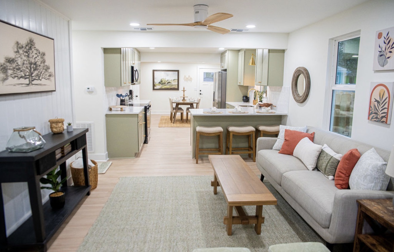 Open concept living room and sage green kitchen staged with neutral furnishings