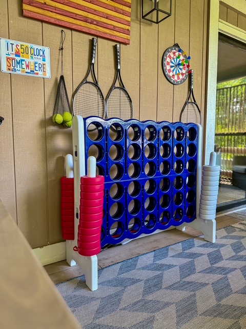 Game corner with giant Connect Four, tennis rackets, and a dartboard on the porch