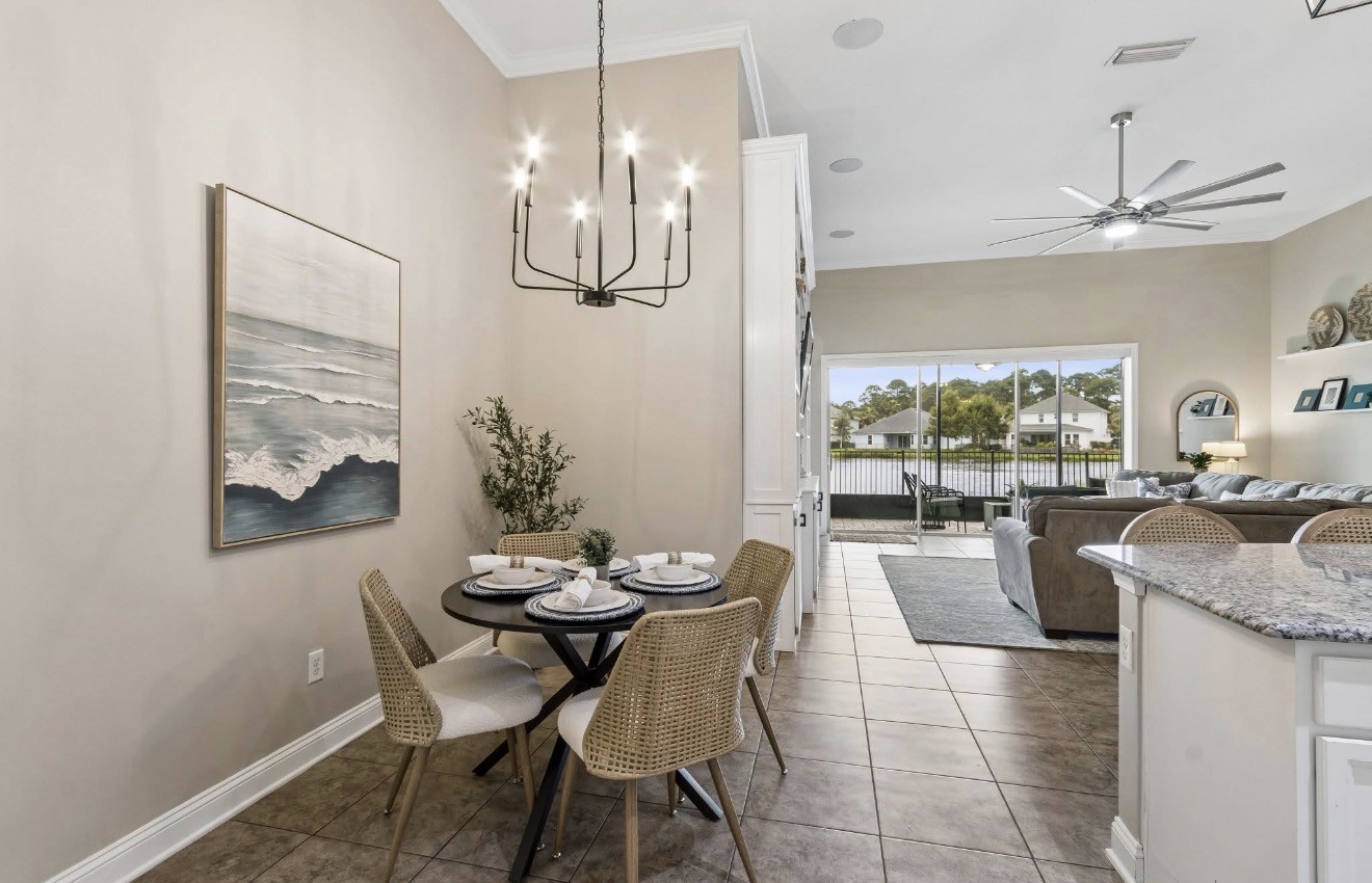 Breakfast nook with round pedestal table, wicker chairs, and coastal artwork beside the kitchen