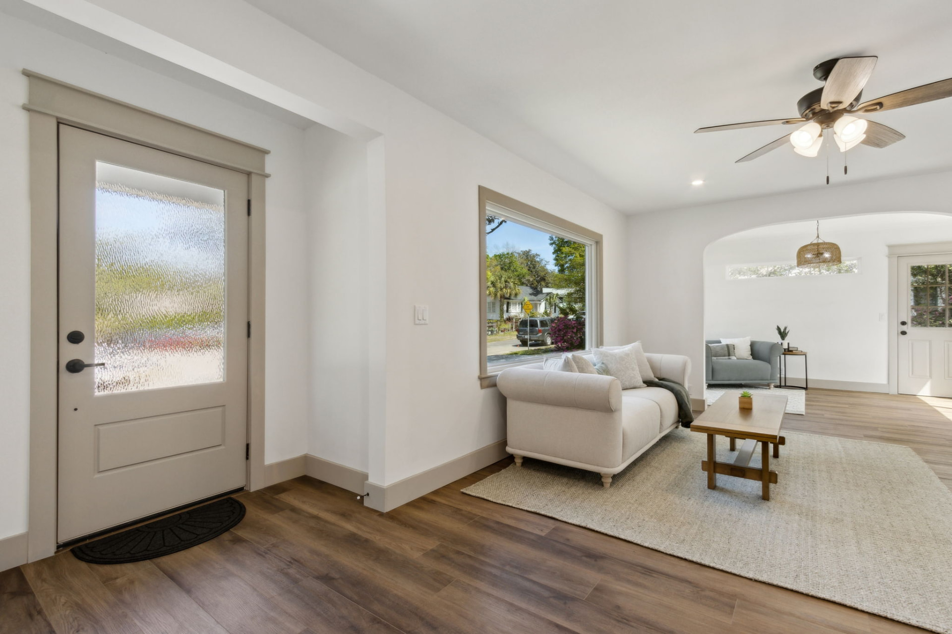 Entry foyer opening into the staged living area with neutral sofa and jute rug
