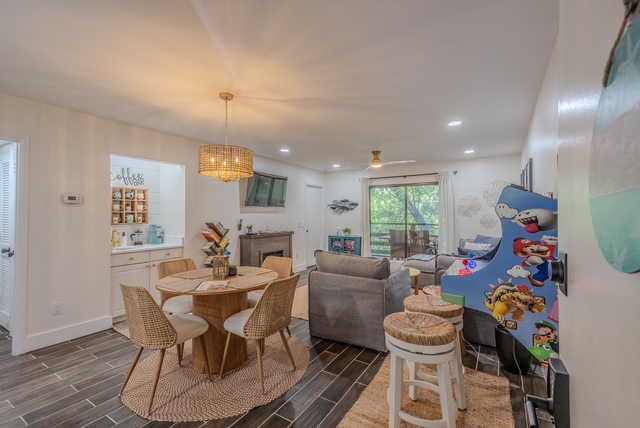 Open living and dining area of an Amelia Island vacation rental with rattan chairs, round table, and woven pendant light