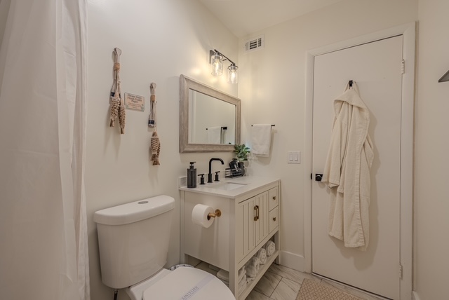 Guest bathroom with framed mirror, coastal wall decor, and a hanging robe