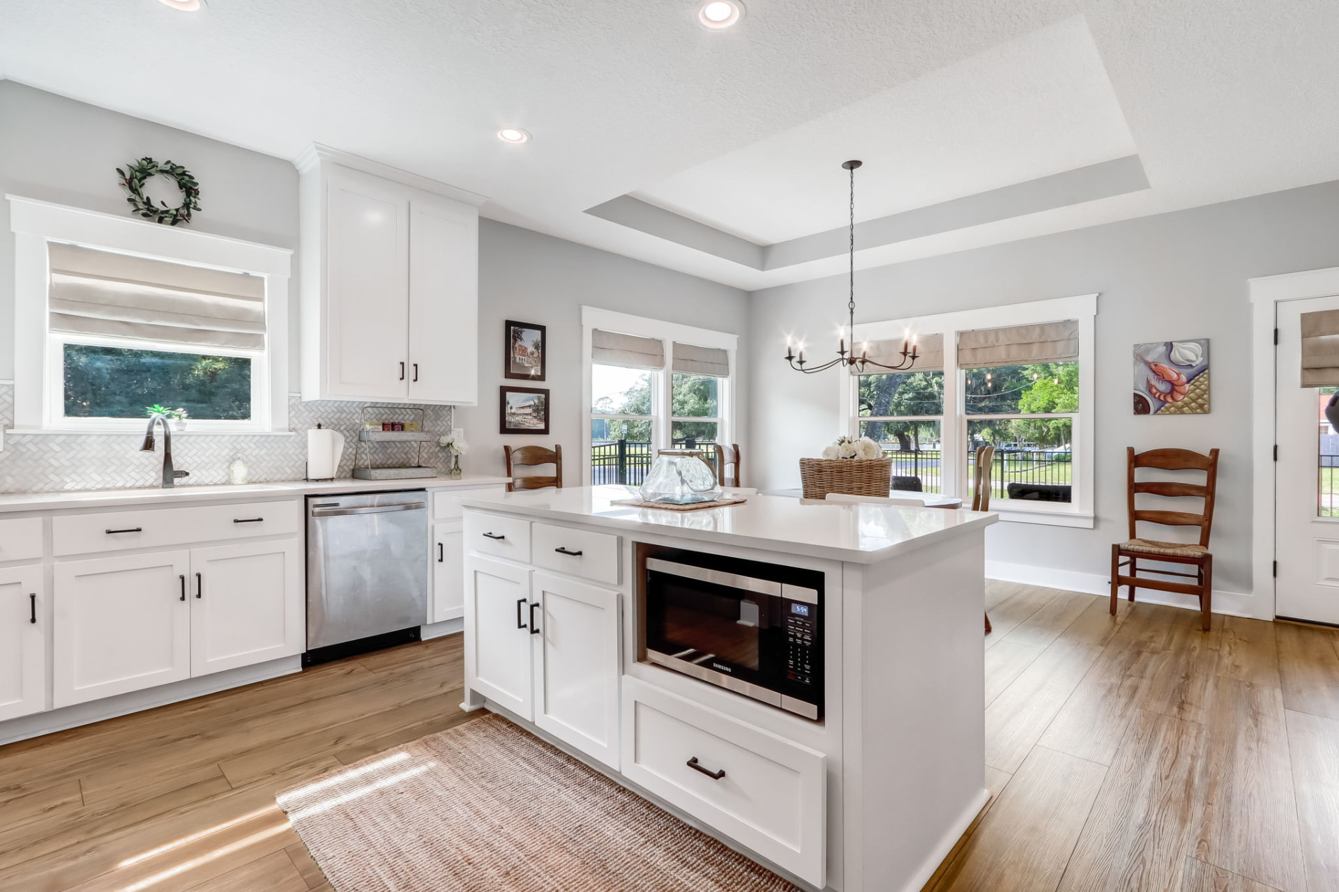 White shaker kitchen with quartz island, herringbone backsplash, and stainless appliances